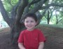 Young boy smiling in front of a tree.