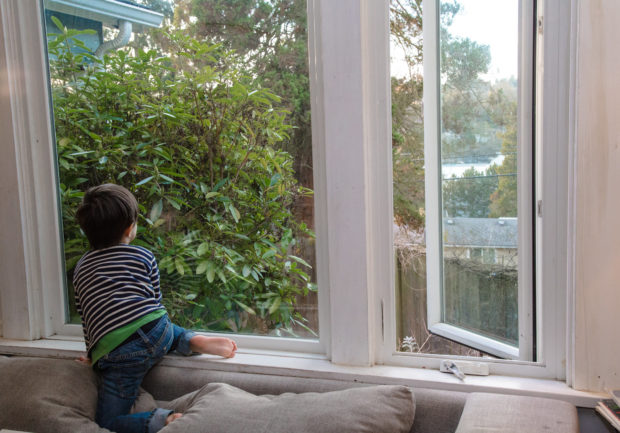 A child sitting on a window sill that has energy efficient window panes