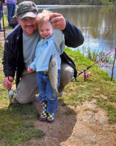 Sam Wurdinger, board member with NWF's Oregon affiliate the Northwest Steelheaders, gets his 2-year-old daughter Grace into her first fish, at annual family fishing event the Steelheaders sponsor. (Photo courtesy the Wurdinger family)