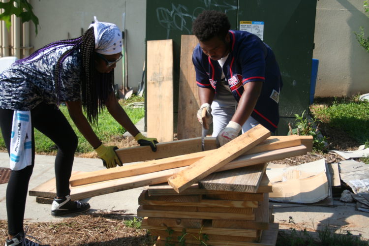 Students cutting wood to build garden bed. Photo by Micalya Hunter 