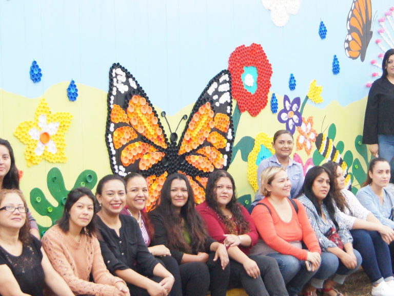 teachers sit in front of a mural