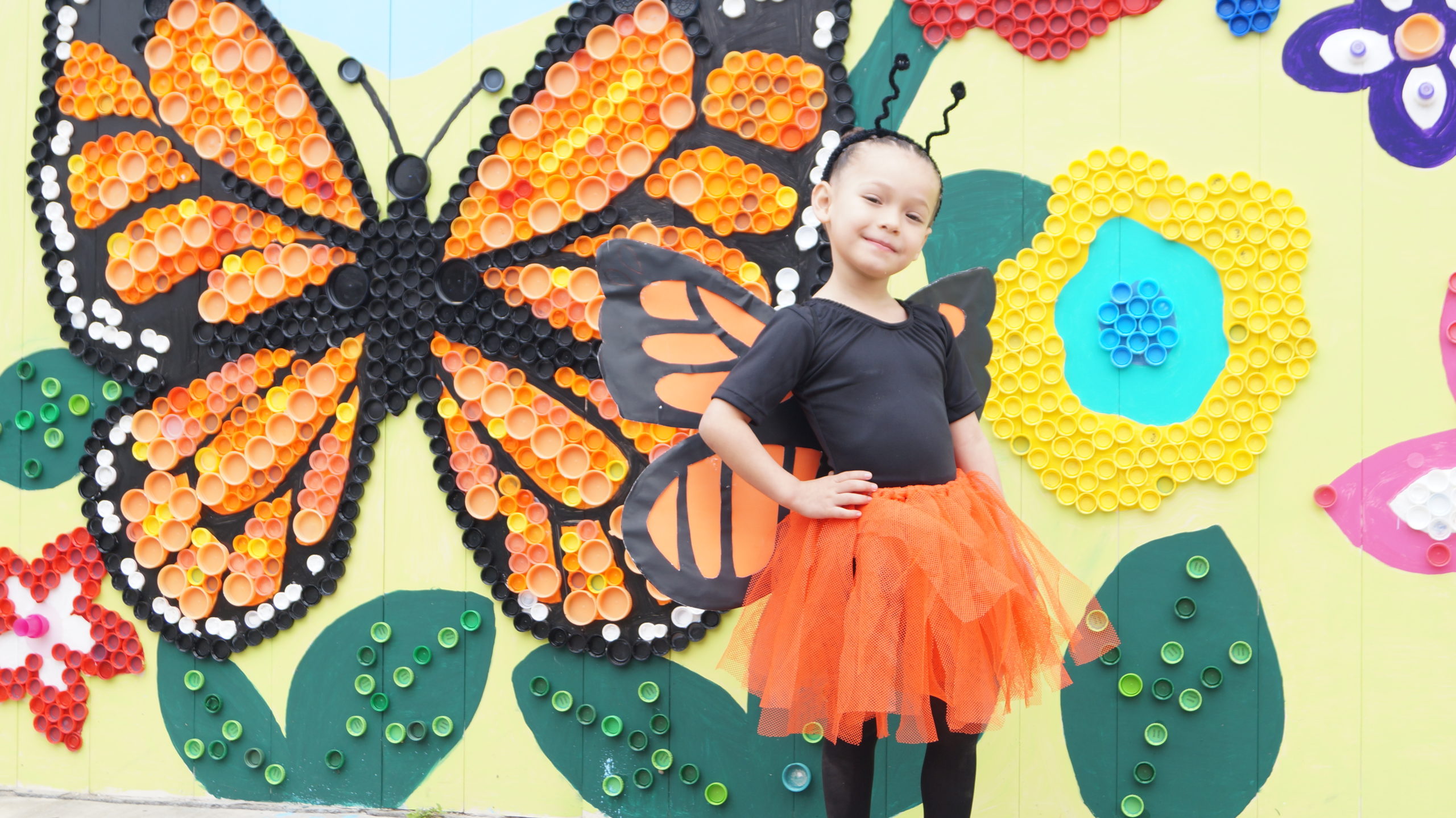 A student poses in front of a mural