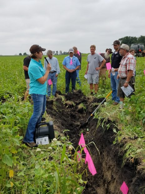 A group of people in a farming field learning about sustainable agriculture