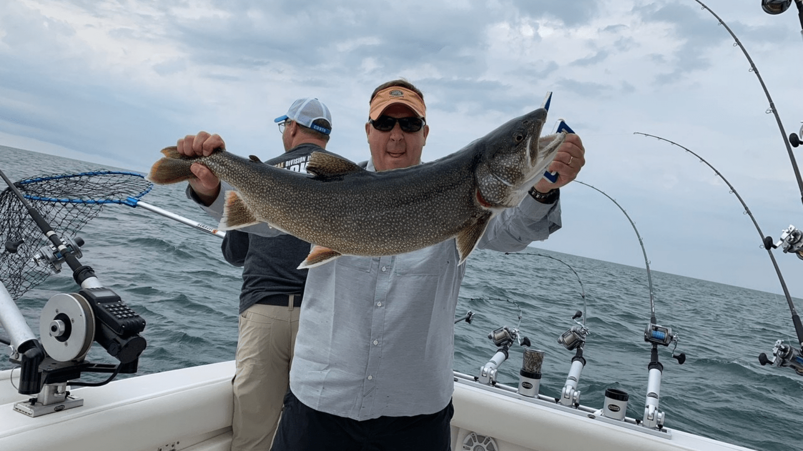 Sportfishing client holds up large catch on boat in the Great Lakes.