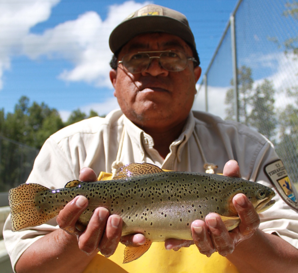 A man holding a trout to the camera
