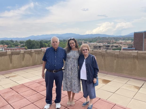Marisa with her abuelos in front of a mountainous backdrop