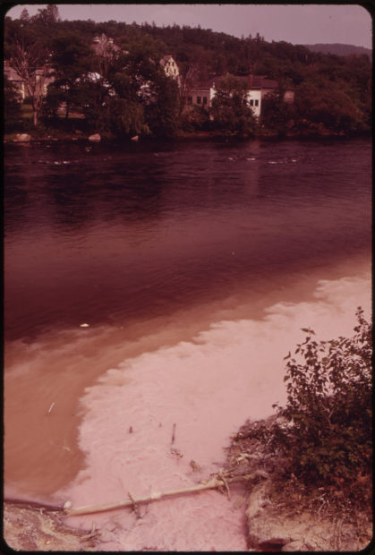 An old photo shows white, foamy pulp flowing directly into a freshwater river.