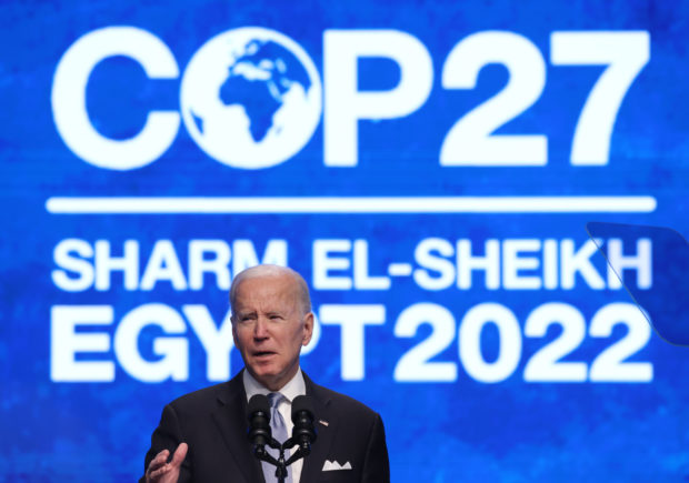 A man stands in front of a podium that reads, "COP27 Egypt 2022".