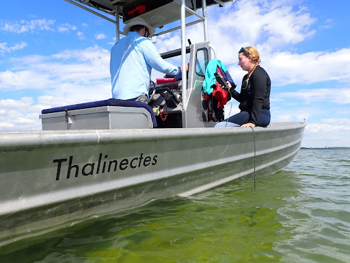 Two people are on a boat named Thalinectes.