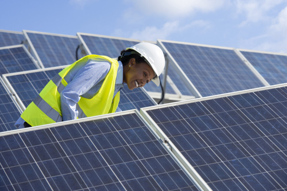 Electrical engineer woman checking solar photovoltaic panels on the roof of a solar farm.