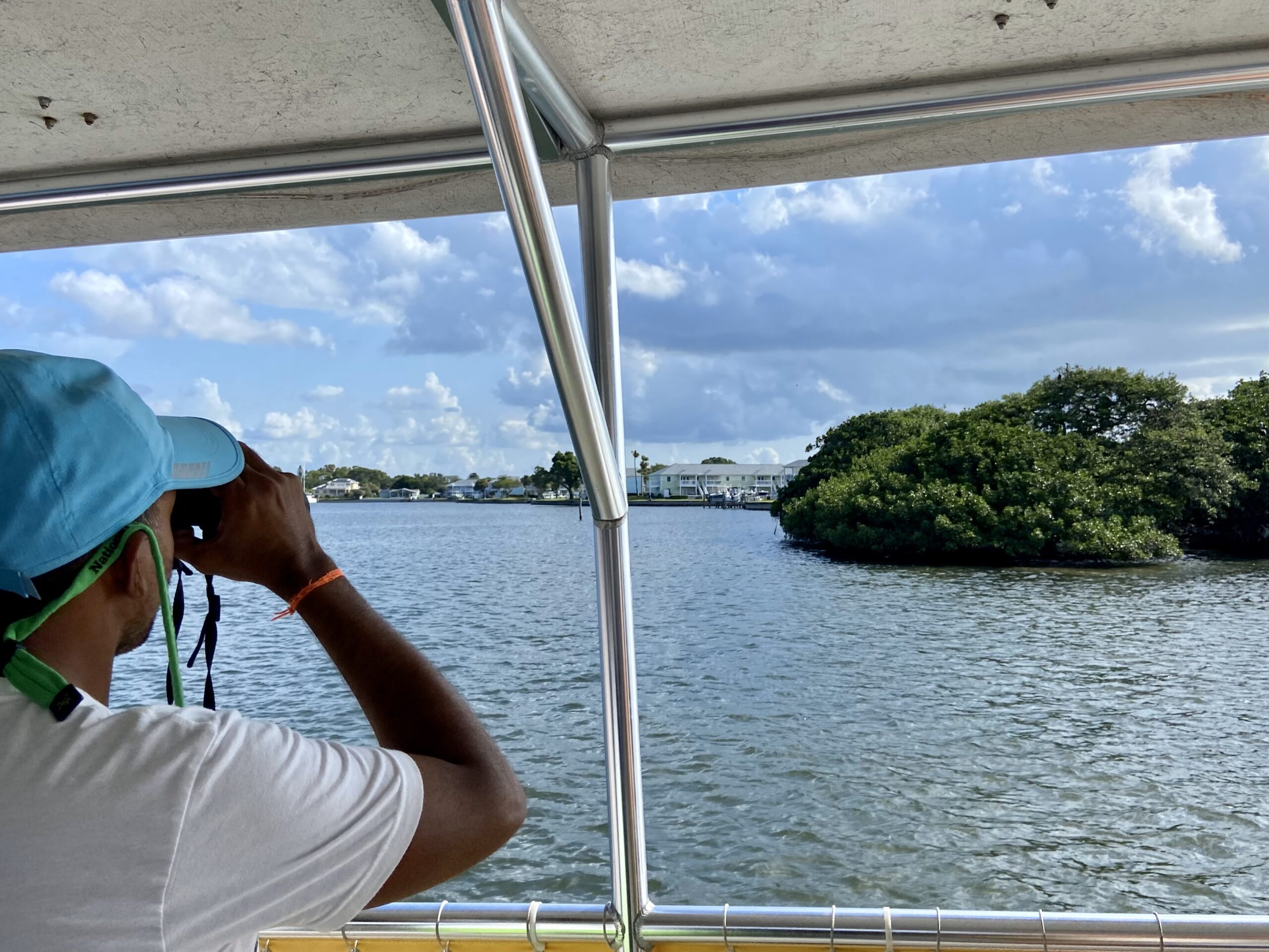 A person on a boat looks out on the water through a pair of binoculars.