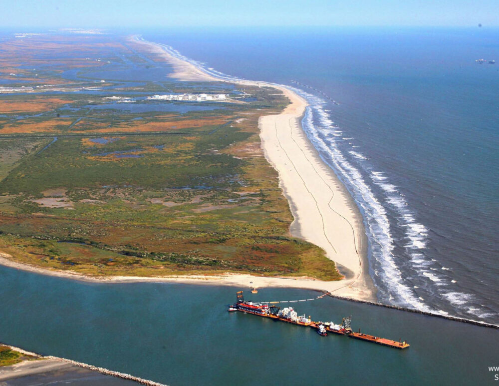 Aerial view of a coastal shore. Restoration rigging and equipment can be seen just offshore.