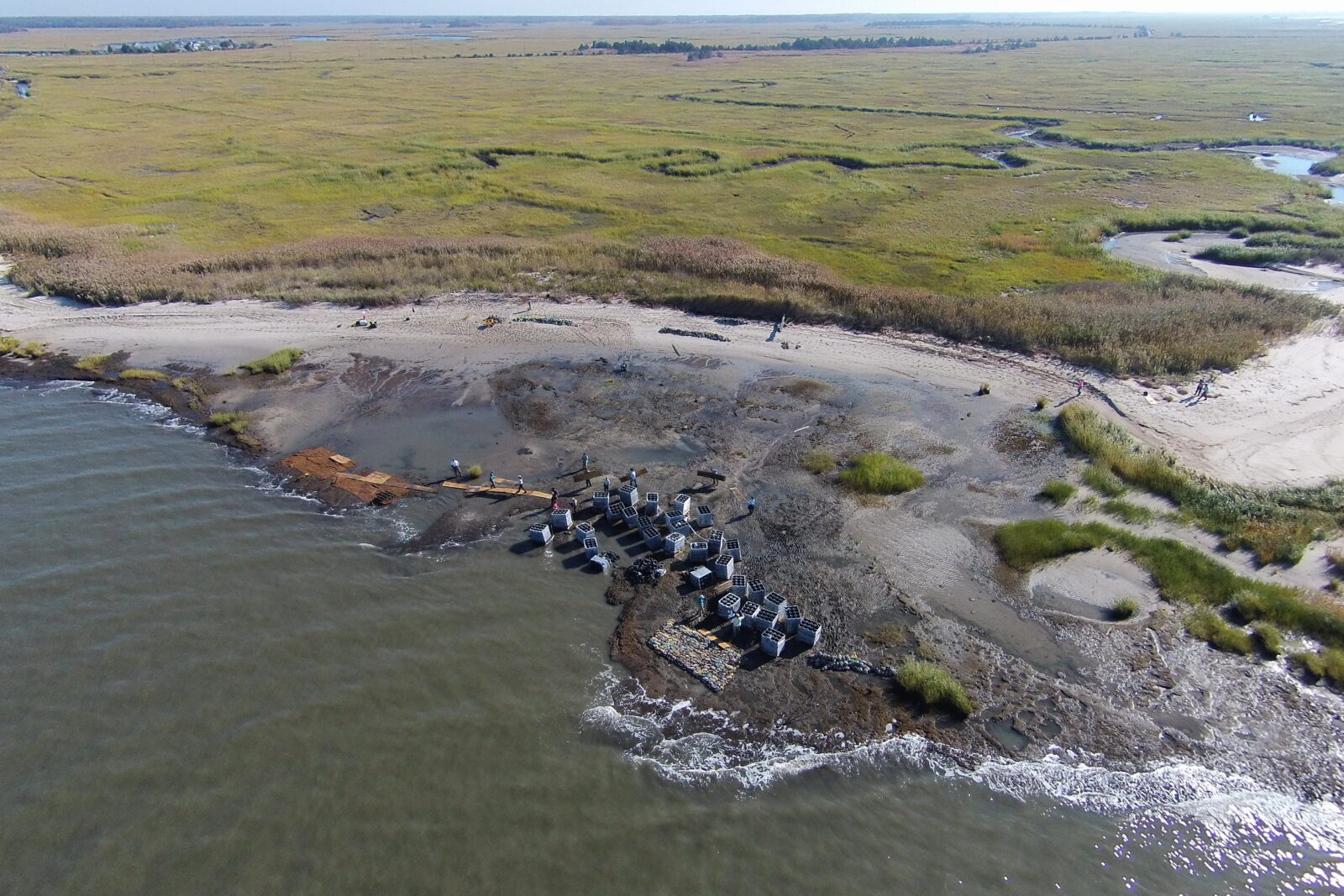 Aerial view of an ongoing restoration project on a coastal shore. Equipment can be seen.