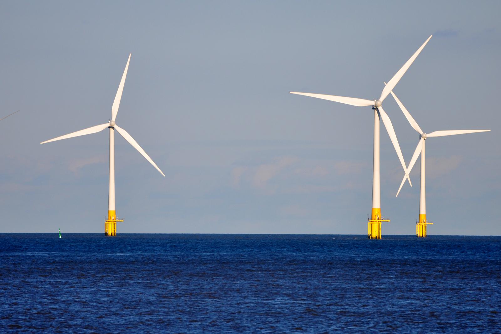 Three offshore wind turbines stand tall in the water.