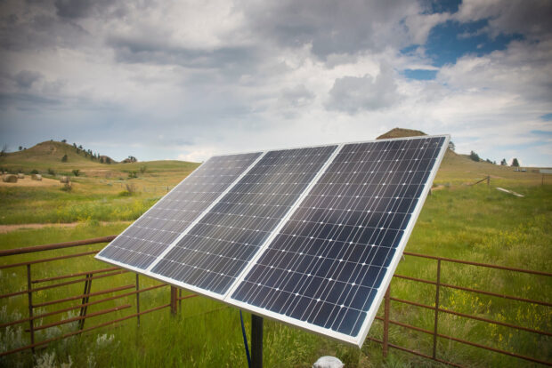 A three-panel solar panel sits in a large field.