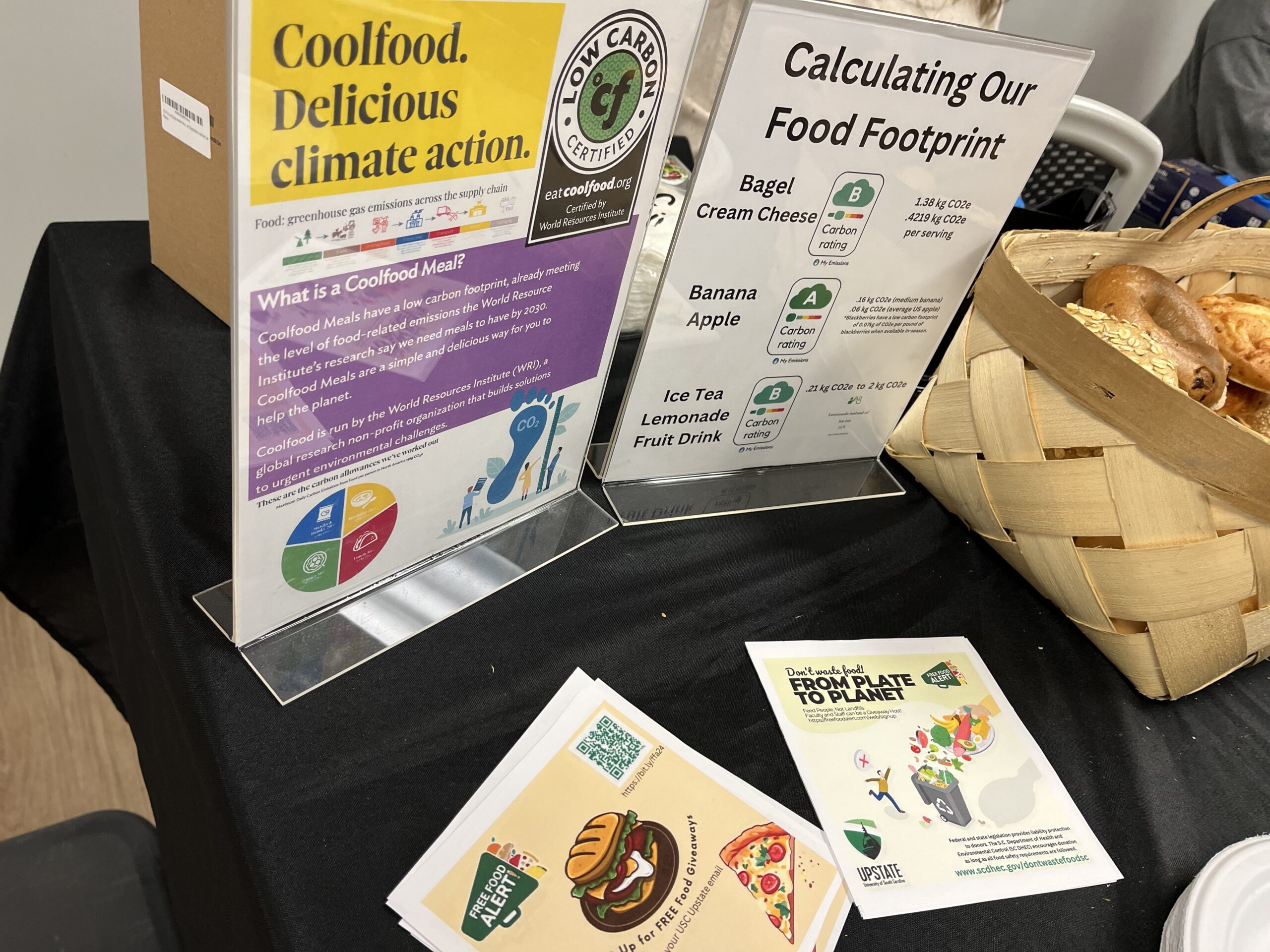 A table features a basket of bagels and signage about food waste.