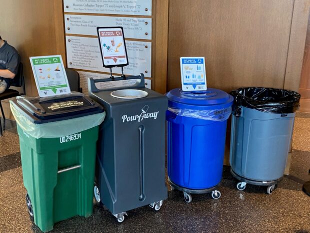 Four different waste bins can be seen with signage indicating an array of waste, recycling, compost, and liquid disposal.