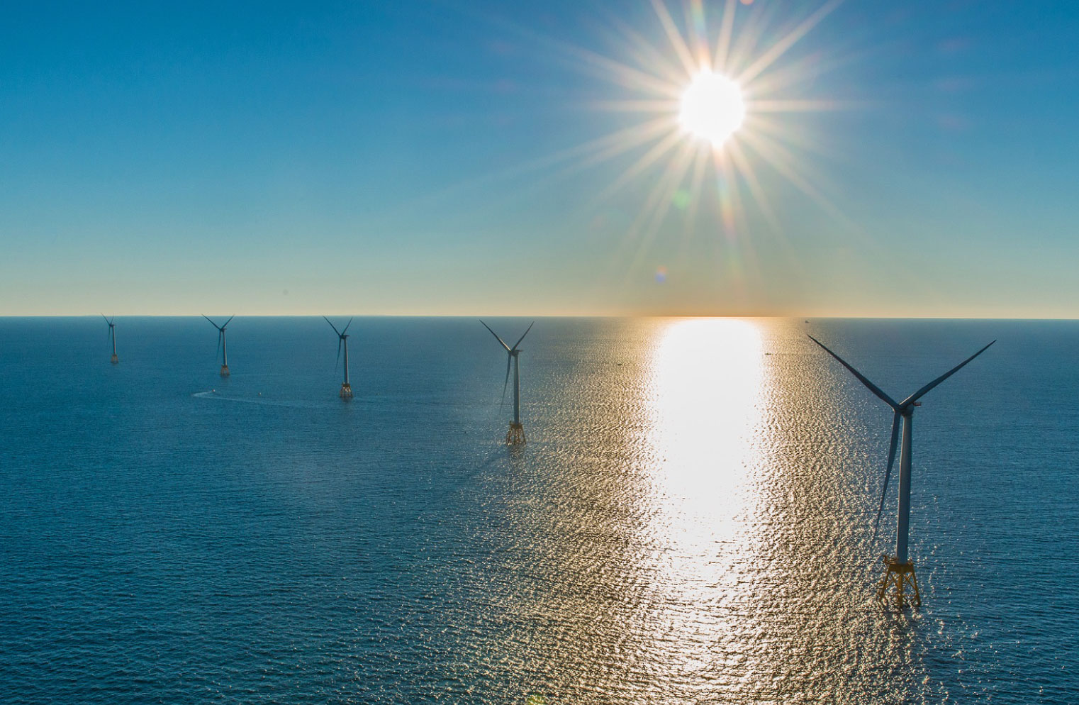 Panoramic view of wind turbines standing in ocean water.