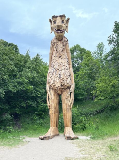 A wooden sculpture depicting a tall troll standing in place.