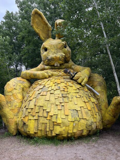 A golden-colored sculpture depicts a large rabbit holding an item in its hand.