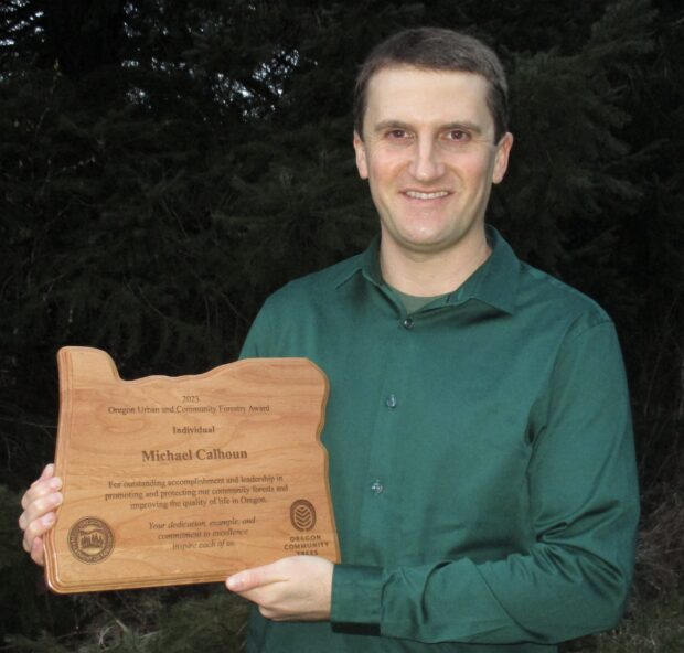 Michael Calhoun holds up his Oregon Urban & Community Forestry Award