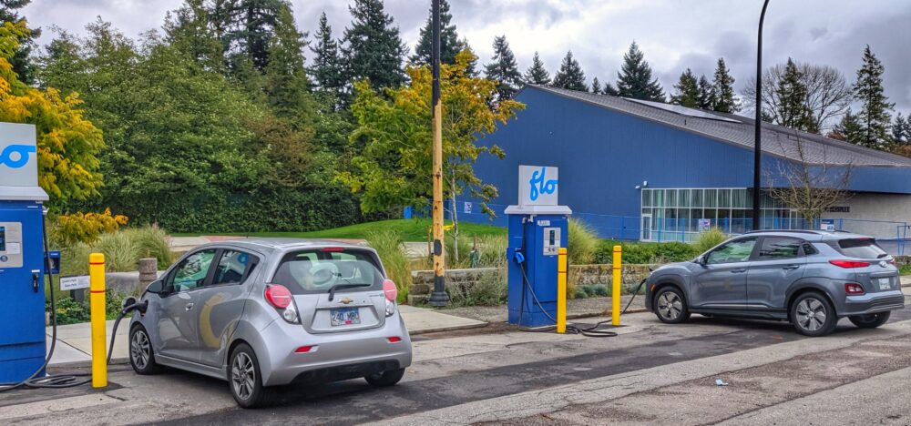 Two electric vehicles charge at a charging station.