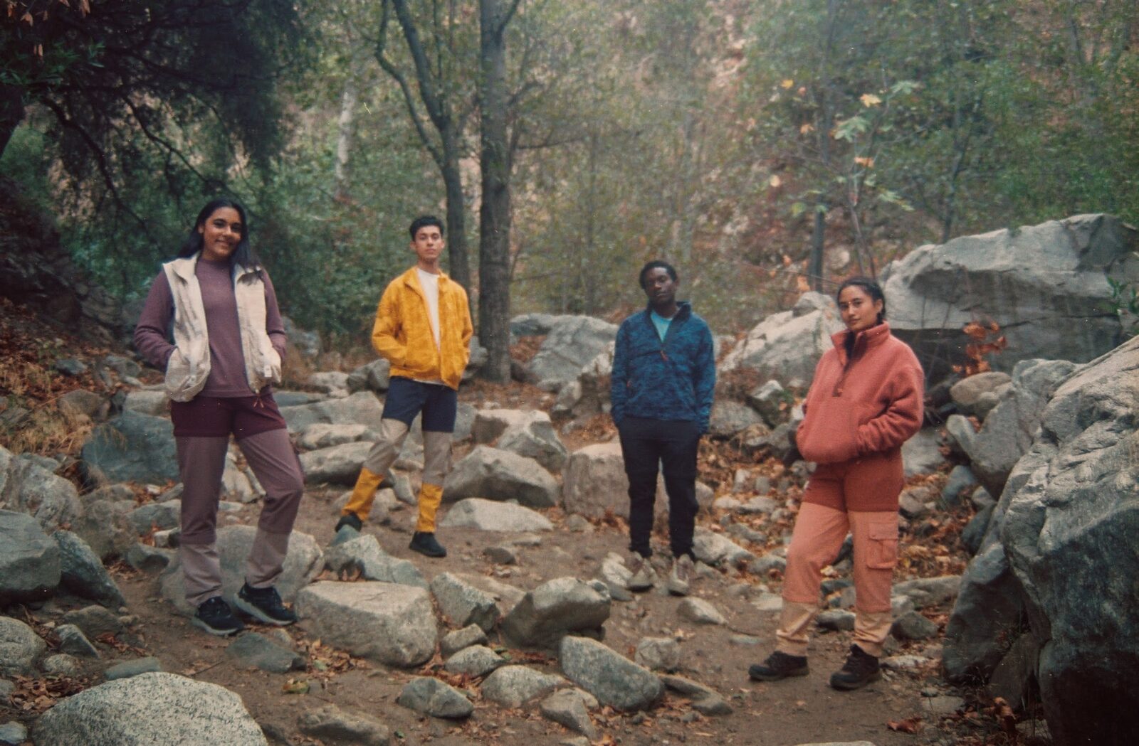 Four people pose for a photo outside in a forest.