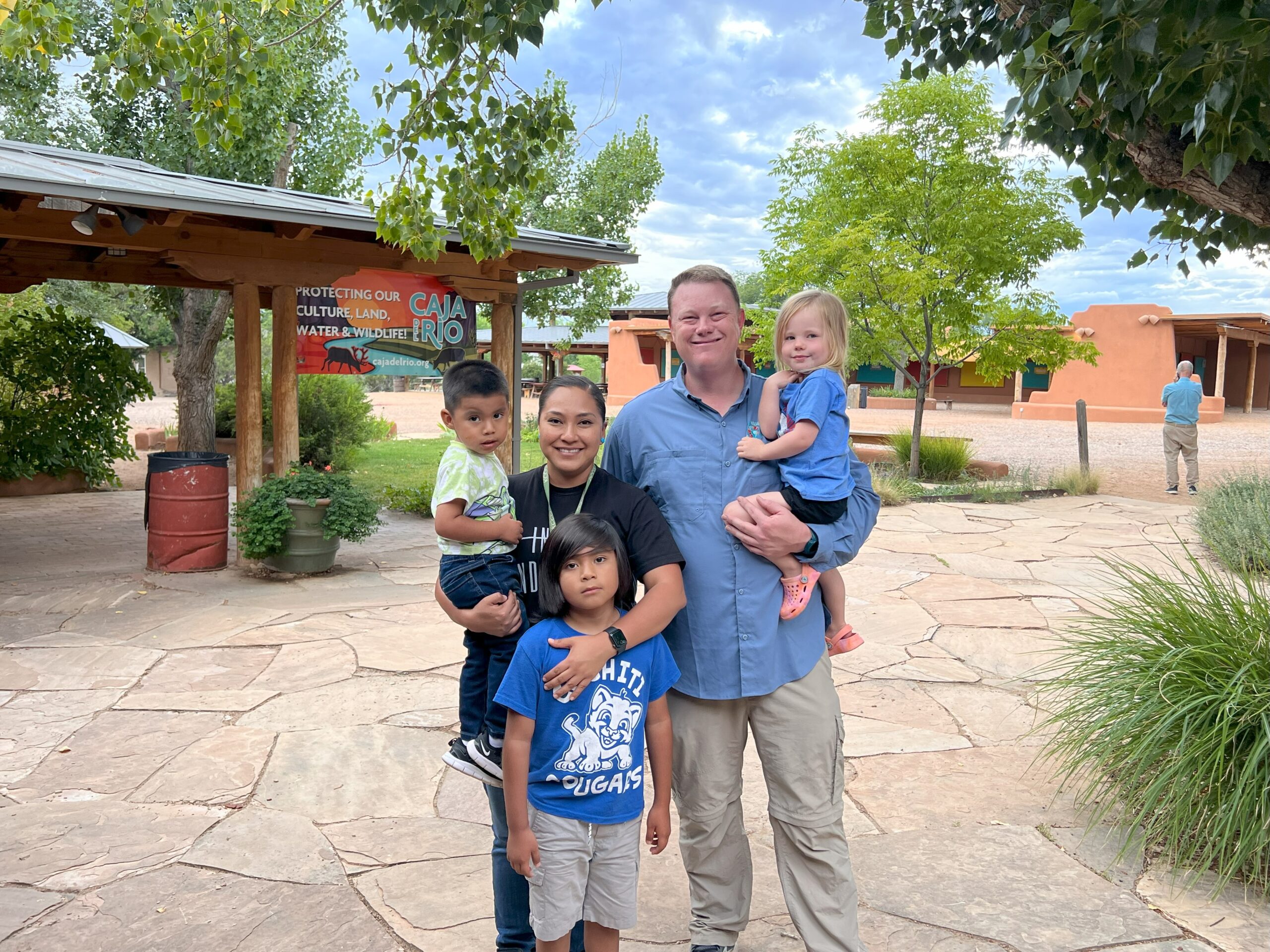 A group of people with three small children pose for a photo outside. 