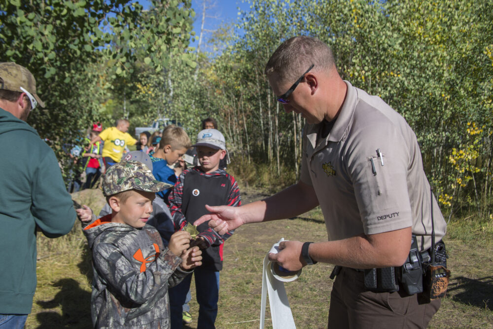 Park rangers lead a group of kids through a forest clearning.