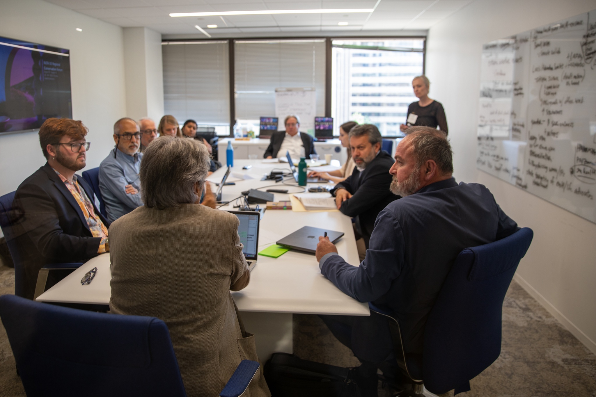 A group of people sit around a table in a meeting room.