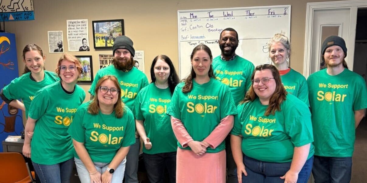 A group of people wearing matching t-shirts pose for a photo.