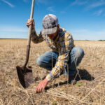 crouching man on a farm with shovel